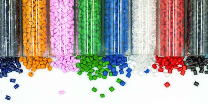 Colored plastic pellets spilling out of glass beakers