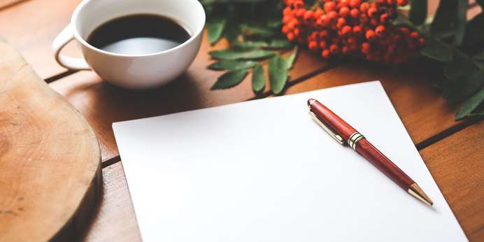 Sheet of paper next to a pen and a coffee cup