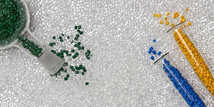 Green, blue, and yellow plastic pellets spilling out of vials into transparent pellets