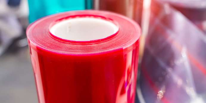 Red roll of sheet plastic next to another roll of opaque sheet plastic