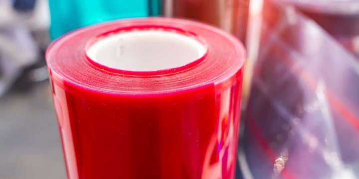 Red roll of sheet plastic next to another roll of opaque sheet plastic