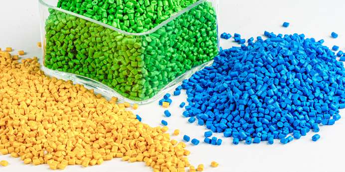 Yellow, green, and blue plastic pellets on a white background